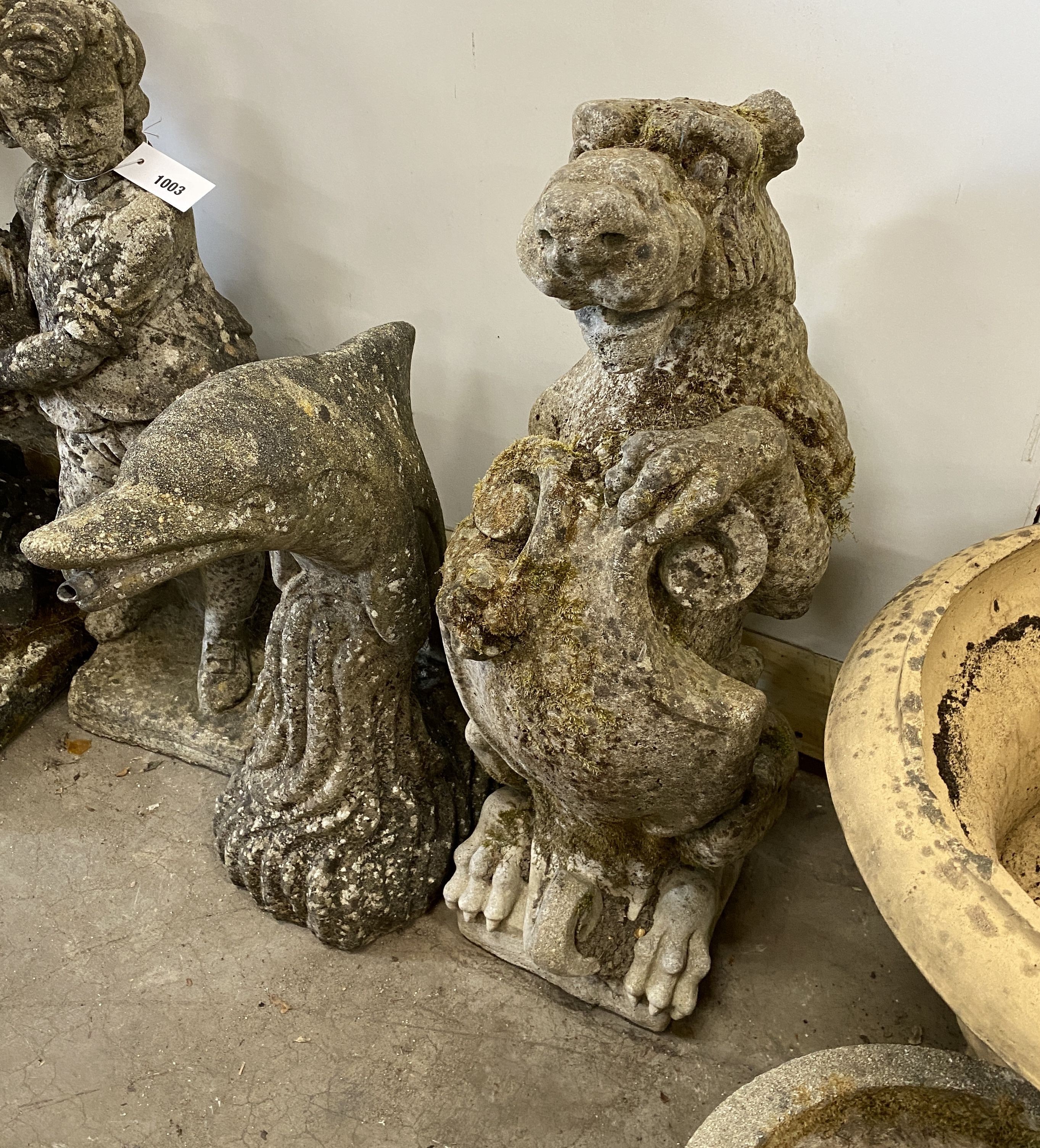 Three reconstituted stone garden ornaments, flower seller, dolphin and heraldic lion, largest height 72cm